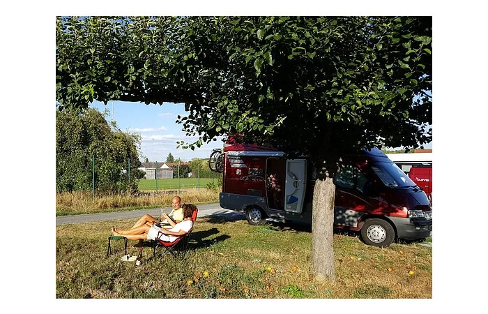 Wohnmobilstellplatz Weingut Staudt Zwei Personen im Liegestuhl mit Weingläser auf einer Wiese. Im Hintergrund Wohnmobile