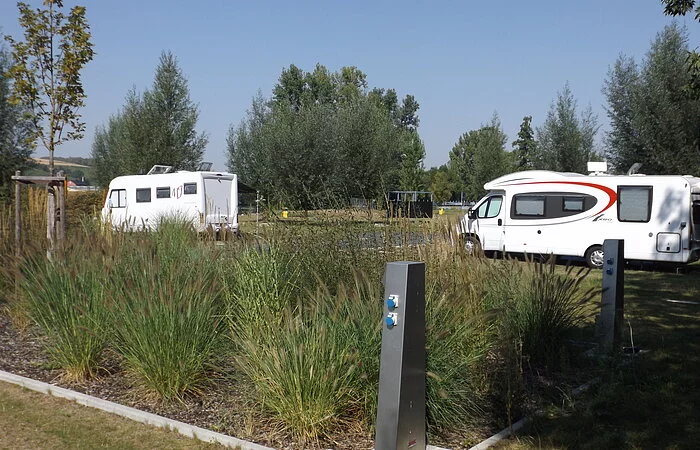 Große Grünfläche mit Wohnmobilen, Bäumen und Büschen