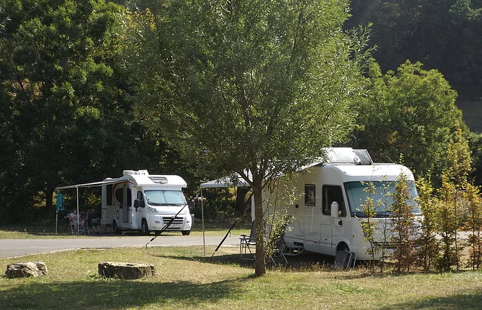 Zwei Wohnmobile unter Bäumen im Grünen