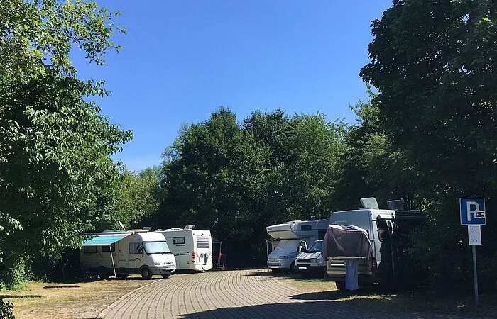 Links und rechts am Weg Wohnmobile mit Bäumen umgeben