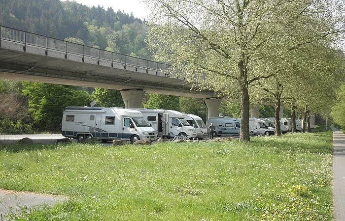 Wohnmobile unter einer Brücke auf der Wiese