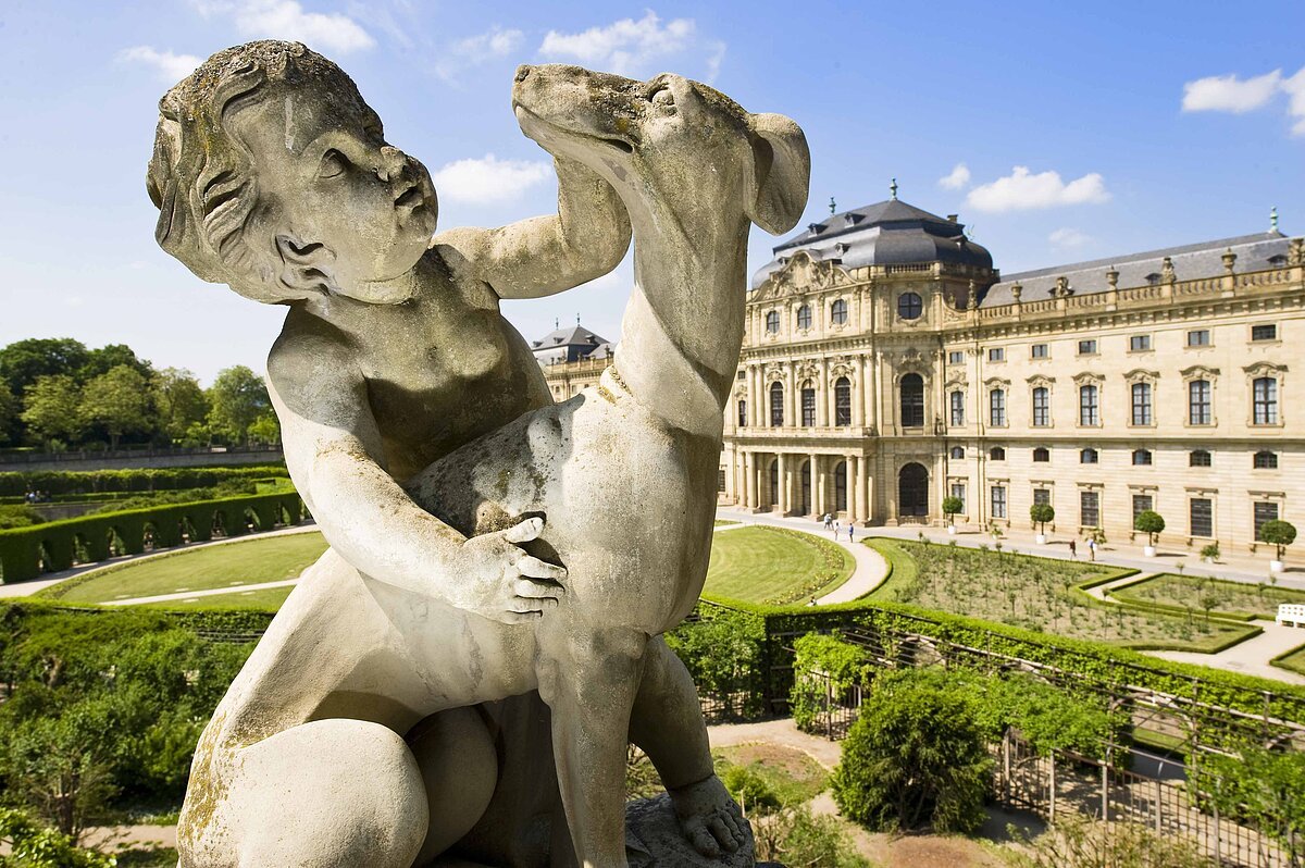 Putto inmitten einer Gartenanlage mit barockem Schloss im Hintergrund
