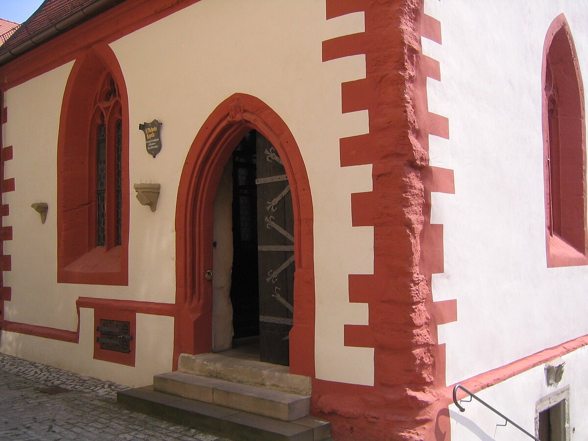 rote einer Kapelle mit rotumrandeten Spitzfenstern und Haupteingang