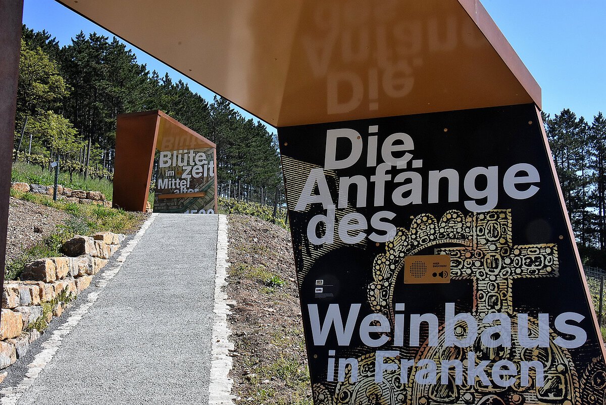 Gehweg mit Cortenstahlelementen daneben und Schriftzug zum Thema des Aussichtspunktes