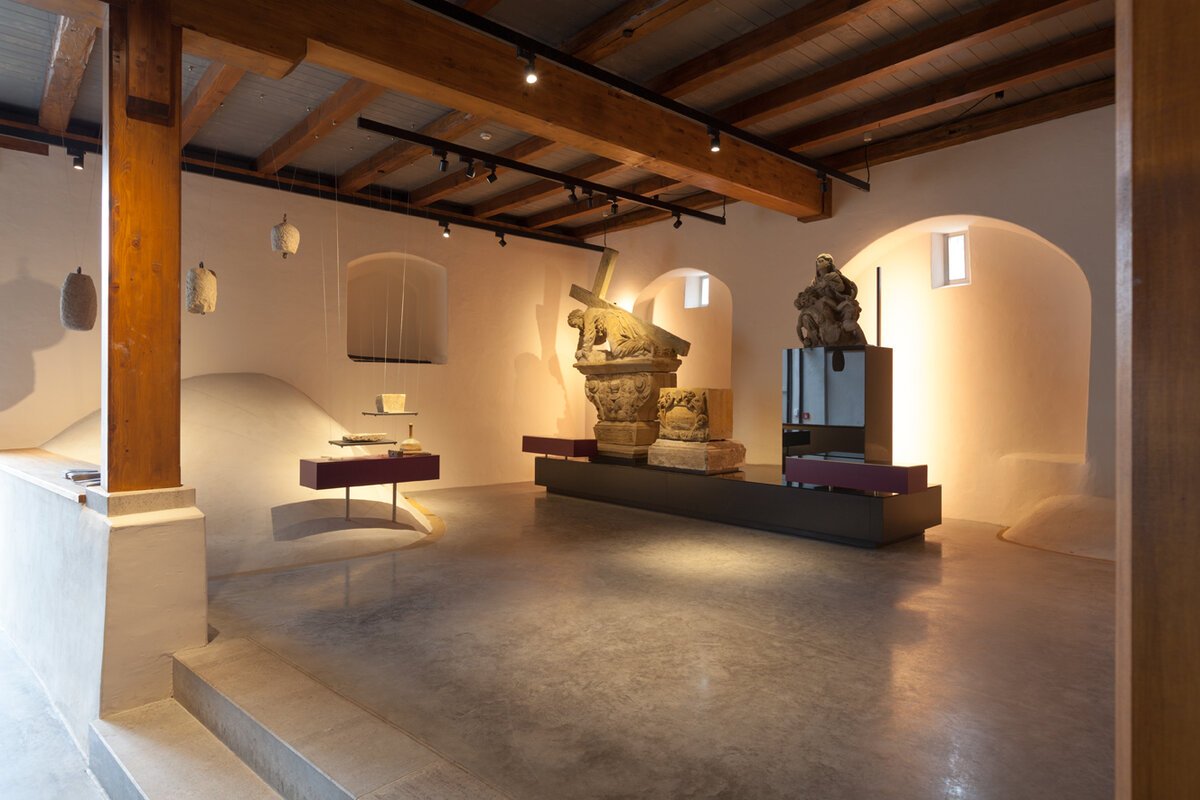 Innenraum mit massiver Holzdecke und Balken mit Ausstellungstücken an der Wand