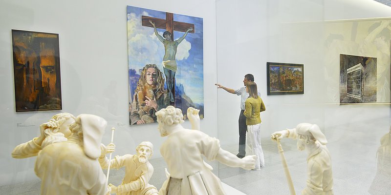 Ausstellungsraum mit Skulpturen und Gemälden plus einer Person